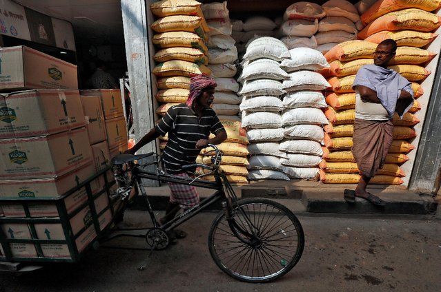 A labourer carries vegetable oil packets on a tricycle as a man stands in front of his shop selling food grains, at a wholesale market in Kolkata, India, January 4, 2017. (Photo by Rupak De Chowdhuri/Reuters)