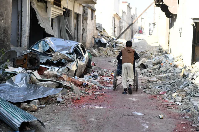 A boy pushes a wheelchair along a damaged street in the east Aleppo neighborhood of al-Mashatiyeh, Syria, in this handout picture provided by UNHCR on January 4, 2017. (Photo by Bassam Diab/Reuters)