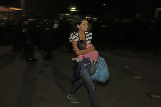 A Honduran migrant carries a baby as she enters Guatemala at the border crossing in Agua Caliente, Guatemala, Tuesday, January 15, 2019. The latest caravan of Honduran migrants hoping to reach the U.S. has crossed peacefully into Guatemala, under the watchful eyes of about 200 Guatemalan police and soldiers. (Photo by Moises Castillo/AP Photo)