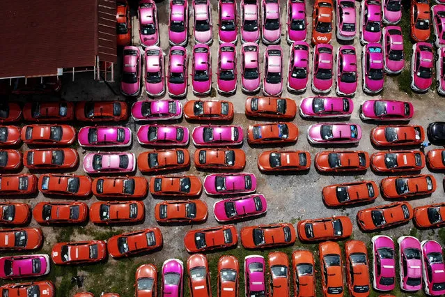 This aerial photo taken on July 20, 2021 shows scores of taxis left in a parking lot, after drivers were unable to pay rent on them due to the economic hardship of Covid-19 and more than a year of no incoming foreign tourism, in Bangkok. Tuk-tuks sitting idle, taxis crammed into empty lots – just some of the vehicles taken off Bangkok's normally riotous roads and stashed in storage as a Covid surge decimates tourism and travel, leaving drivers out of pocket. (Photo by Lillian Suwanrumpha/AFP Photo)