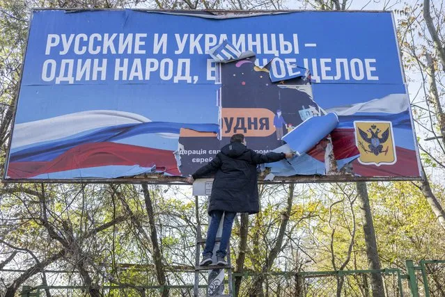 A man removes a banner from Russian occupation period “Russians and Ukrainians are one people, one whole” in the newly liberated Kherson on November 14, 2022, amid Russia's invasion of Ukraine. The takeover by Ukrainian troops of the Kherson region is the latest in a string of setbacks for Russia, which invaded Ukraine on February 24 hoping for a lightning takeover and to topple the government in days. (Photo by Bulent Kilic/AFP Photo)