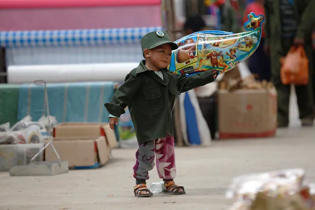 A boy dressed as a United Wa State Army (UWSA) soldier, plays in a market at Mongmao, Wa territory in northeast Myanmar October 1, 2016. (Photo by Soe Zeya Tun/Reuters)
