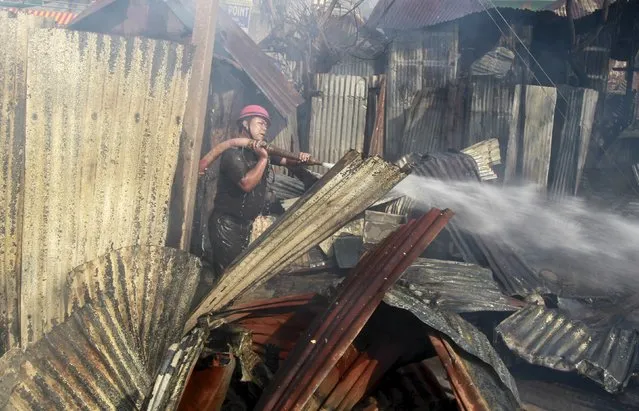 A firefighter tries to extinguish a fire in a slum area in Agartala, India, March 5, 2016. Several huts were gutted in the fire but no casualties were reported, a fire official said on Saturday. (Photo by Jayanta Dey/Reuters)
