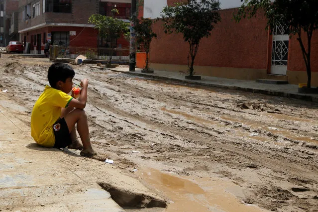 A child sits on a street pavement after a landslide and a flood occurred in San Juan de Lurigancho distritct, in Lima, Peru February 1, 2017. (Photo by Guadalupe Pardo/Reuters)