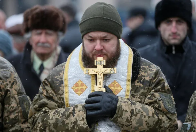 A chaplain waits for a funeral ceremony for Ukrainian serviceman Leonid Derhach, who was recently killed during a military conflict in the east of the country, in Independence Square in Kiev, Ukraine February 3, 2017. (Photo by Valentyn Ogirenko/Reuters)