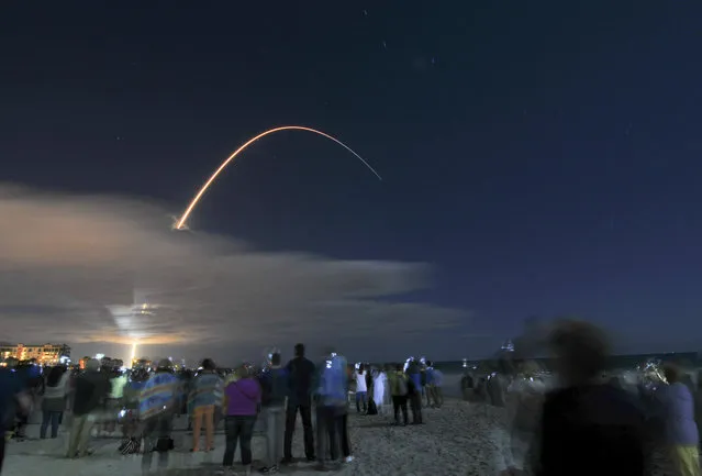 In this photo taken with a long exposure, hundreds line the beach north of the Cocoa Beach Pier in Florida to watch launch of the Orbital ATK's Cygnus spacecraft off the United Launch Alliance Atlas V rocket at Cape Canaveral Air Force Station, Tuesday, March 22, 2016. (Photo by Malcolm Denemark/Florida Today via AP Photo)