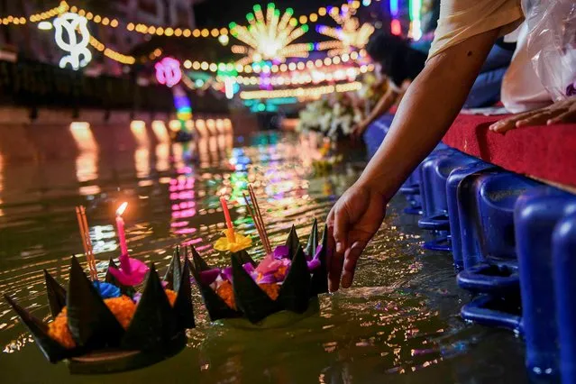People gather to place krathongs (floating baskets) into a canal during the Loy Krathong festival, which is held as a symbolic apology to the goddess of the river in Bangkok, Thailand, November 19, 2021. (Photo by Chalinee Thirasupa/Reuters)