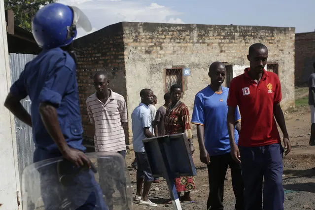 Local residents walk past police in the Musaga district of Bujumbura, Burundi, Sunday May 10, 2015. (Photo by Jerome Delay/AP Photo)