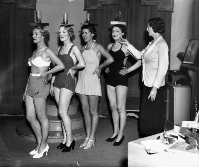 1936:  Lucie Clayton instructs pupils in the art of correct posture by balancing a glass and book on their heads at her finishing school