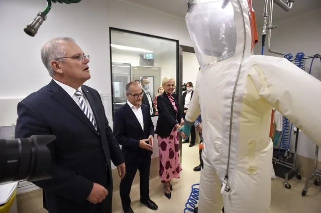 Australian Prime Minister Scott Morrison, left, looks at a hazard suit during a tour at the Peter Doherty Institute for Infection and Immunity in Melbourne, Tuesday, December 14, 2021. Australia's government said Tuesday it plans to start making mRNA vaccines at home with a new plant that could produce up to 100 million doses each year. (Photo by Andrew Henshaw/AAP Image via AP Photo)
