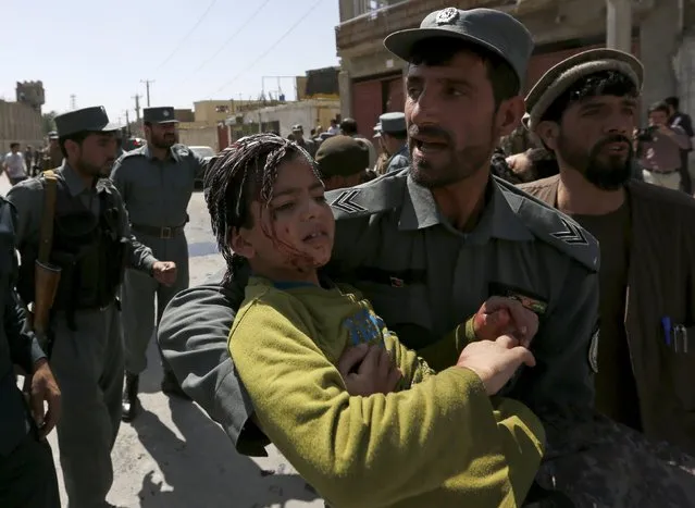 An Afghan policeman carries an injured boy from site of an attack in Kabul, Afghanistan May 17, 2015. A car bomb rammed a convoy of foreign troops near the main airport in Afghanistan's capital on Sunday, killing at least three civilians in the latest attack in the city, police and a witness said. (Photo by Mohammad Ismail/Reuters)
