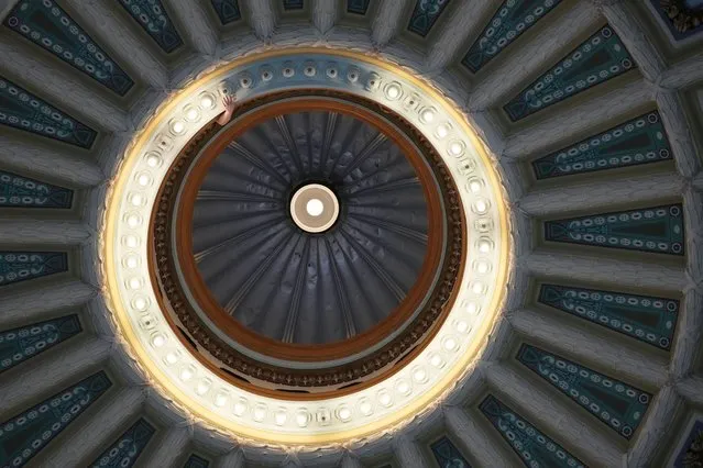 A Mississippi State Capitol facilities worker reaches out to remove a burned out light bulb in the main dome that graces the rotunda of the Capitol in Jackson, Miss. Monday, April 8, 2024. (Photo by Rogelio V. Solis/AP Photo)