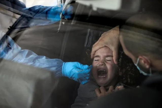 A girl is tested for the coronavirus disease (COVID-19) at a drive-through site as Israel faces a surge in Omicron variant infections, in Jerusalem on January 3, 2022. (Photo by Ammar Awad/Reuters)
