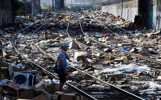 Local resident Luke Mines takes photos as he looks at the mess on railway tracks littered with the remains of items stolen from passing freight trains, in Los Angeles. California. U.S., January 14,2022. (Photo by Gene Blevins/Reuters)