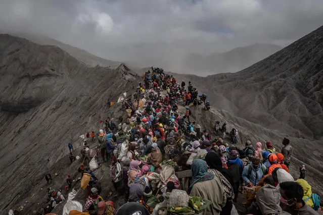 Tenggerese gather at crater of Mount Bromo during the Yadnya Kasada Festival on July 18, 2019 in Probolinggo, East Java, Indonesia. Tenggerese people are a Javanese ethnic group in Eastern Java who claimed to be the descendants of the Majapahit princes. Their population of roughly 500,000 is centered in the Bromo Tengger Semeru National Park in eastern Java. The most popular ceremony is the Kasada festival, which makes it the most visited tourist attraction in Indonesia. The festival is the main festival of the Tenggerese people and lasts about a month. On the fourteenth day, the Tenggerese made a journey to Mount Bromo to make offerings of rice, fruits, vegetables, flowers and livestock to throw them into the volcano's caldera. The origin of the festival lies in the 15th century princess named Roro, the principality of Tengger with her husband Joko Seger, and the childless couple asked mountain Gods for help in bearing children. The legend says the Gods granted them 24 children but on the provision that the 25th must be added to the volcano in sacrifice. The 25th child, Kesuma, was finally sacrificed in this initial after refusal, and the tradition of throwing sacrifices into the Caldera to appease the mountain Gods continues today. (Photo by Ulet Ifansasti/Getty Images)