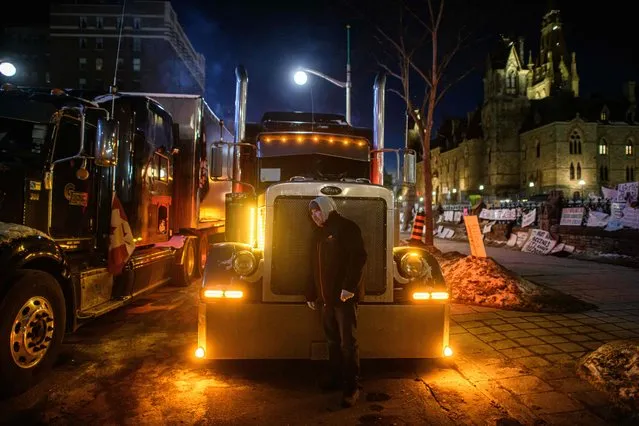A truck driver listens to the engine of his truck during a protest over pandemic health rules and the Trudeau government, outside the parliament of Canada in Ottawa on February 14, 2022. Canadian Prime Minister Justin Trudeau on Monday invoked rarely used emergency powers to bring an end to trucker-led protests against Covid health rules, after police arrested 11 people with a “cache of firearms” blocking a border crossing with the United States. (Photo by Ed Jones/AFP Photo)