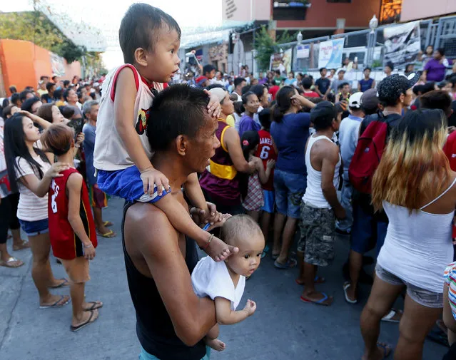 A father carries his children as they wait for the campaign motorcade of presidential candidate Vice-president Jejomar Binay and Filipino boxer and Congressman Manny Pacquiao, who is running for senator in Monday's national elections, to pass by during their campaign sortie in Navotas north of Manila, Philippines Friday, May 6, 2016. (Photo by Bullit Marquez/AP Photo)