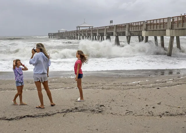 Juna Beach residents Anneka, 8, left, and sister, Breanna, 10, right, along with their mother, Leah Hanza, center, get a close look of the waves crashing against the Juno Beach Pier as Hurricane Dorian crawls toward Florida, and it continues to ravage the Bahamas on Monday, September 2, 2019. (Photo by Carl Juste/Miami Herald via AP Photo)