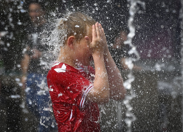 A child plays with water to cool off himself in front of the Uber Arena as daily life continues in Berlin, Germany on May 26, 2024. (Photo by Halil Sagirkaya/Anadolu via Getty Images)