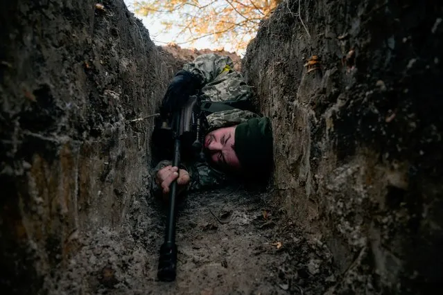 A Ukrainian soldier hides from a helicopter airstrike amid Russia's invasion of Ukraine, near Demydiv, Ukraine on March 10, 2022. (Photo by Maksim Levin/Reuters)