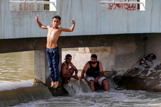 A boy reacts as he jumps to dive into a canal of the Tigris river in Baghdad amid a soaring heatwave on June 18, 2024 on the third day of the Muslim holiday of Eid al-Adha. (Photo by Ahmad Al-Rubaye/AFP Photo)