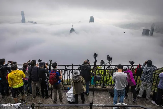 People take photographs of fog over Hong Kong on March 22, 2022. (Photo by Dale de la Rey/AFP Photo)