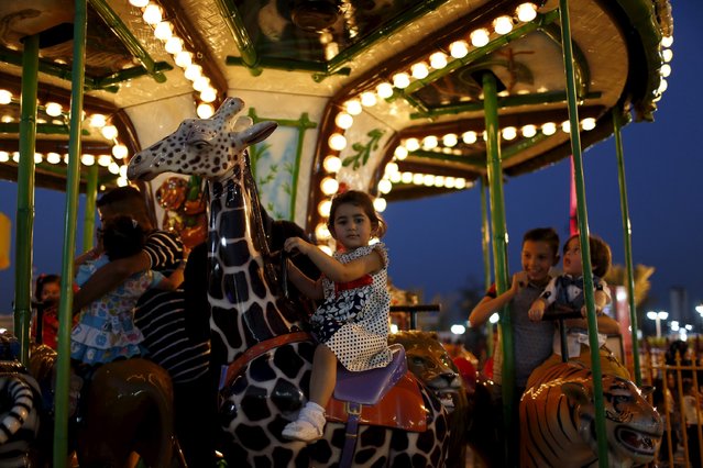 A child enjoys a ride in an amusement park during Eid al-Fitr celebrations, marking the end of the Muslim fasting month of Ramadan, in Baghdad, July 17, 2015. (Photo by Thaier al-Sudani/Reuters)