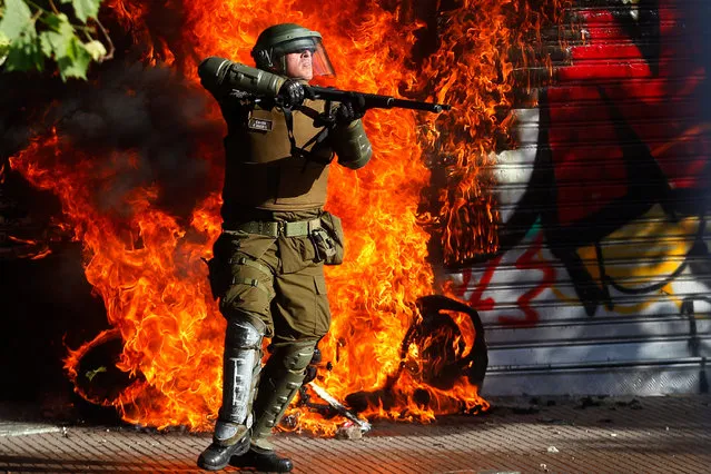 A member of the riot police gets ready to repel the attacks of protesters during a protest against President Sebastian Piñera during the seventh day of protests against President Sebastian Piñera on October 24, 2019 in Santiago, Chile. Although President Sebastian Piñera announced measures to improve equality, unions called for a national strike and demonstrations continue as casualties are now at least 18. Demands behind the protest include issues like health care, pension system, privatization of water, public transport, education, social mobility and corruption. (Photo by Marcelo Hernandez/Getty Images)