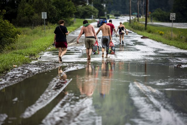 Residents walk barefoot away from flood damage in Lyndon, Vt., Tuesday, July 30, 2024. (Photo by Dmitry Belyakov/AP Photo)