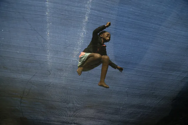 Twelve year-old girl Simphiwe Gama enjoys jumping on a trampoline in Katlehong, about 30Km east of Johannesburg, South Africa, Monday, July 13, 2015. The trampoline is set up by a resident and operated for the local community, charging 50 cents for five minutes of jumping fun. (Photo by Themba Hadebe/AP Photo)