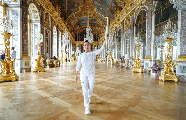 This handout photograph taken and released by The Paris 2024 press services on July 23, 2024, shows Mexican American actress Salma Hayek as she walks with the Olympic Torch as part of the 2024 Paris Olympic Games Torch Relay in The Hall of Mirrors (Galerie des Glaces) at Chateau de Versailles, west of Paris. (Photo by Laurent Vu/Paris 2024/AFP Photo)