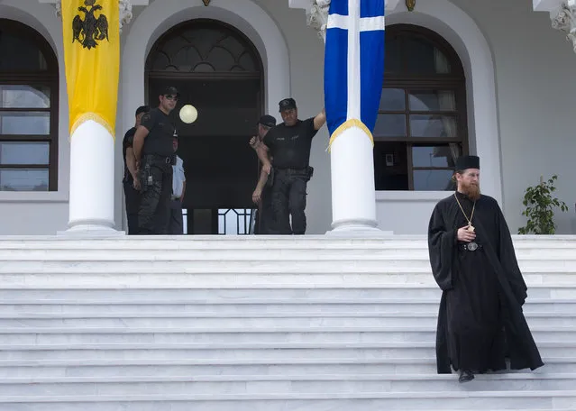 An Orthodox monk walks down the steps as Greek police provide security at a palace in Karyes, the capital of Mount Athos, Greece, Friday, May 27, 2016. (Photo by Darko Bandic/AP Photo)