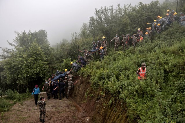 Security force personnel carry bodies of victims at the site of a helicopter crash on the outskirts of Kathmandu, Nepal, on August 7, 2024. (Photo by Navesh Chitrakar/Reuters)