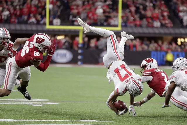 Ohio State wide receiver Chris Olave (17) is tackled by Wisconsin safety Reggie Pearson (2) as linebacker Zack Baun (56) watches during the second half of the Big Ten championship NCAA college football game Saturday, December 7, 2019, in Indianapolis. (Photo by Michael Conroy/AP Photo)