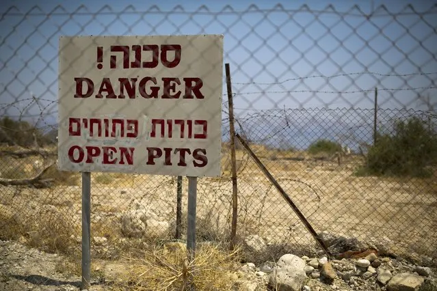 A sign warning of sinkholes is seen on a fence surrounding an abandoned holiday resort on the shore of the Dead Sea near Kibbutz Ein Gedi, Israel July 27, 2015. (Photo by Amir Cohen/Reuters)