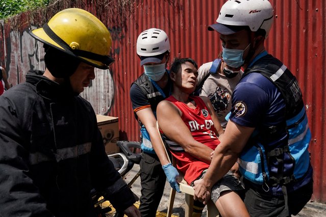 Rescuers carry a man during a fire at a building in Manila, Philippines, on August 2, 2024. (Photo by Lisa Marie David/Reuters)