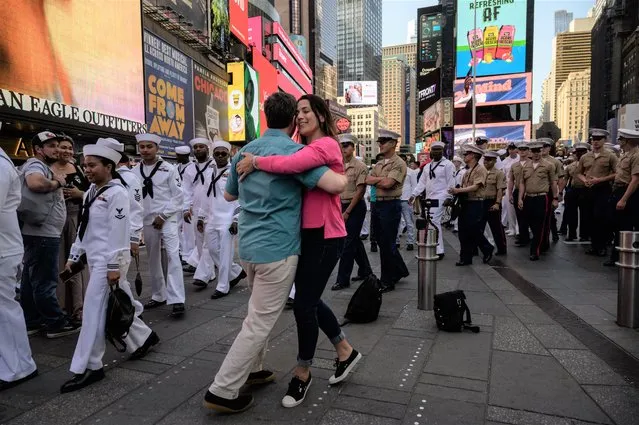 US servicemembers walk past a couple dancing in Times Square, as part of “Fleet Week” celebrations in New York on May 25, 2022. Fleet Week is a week-long celebration of sea services which aims to provide an opportunity for members of the public to meet sailors, marines, and coastguard personnel through various events and displays. (Photo by Ed Jones/AFP Photo)