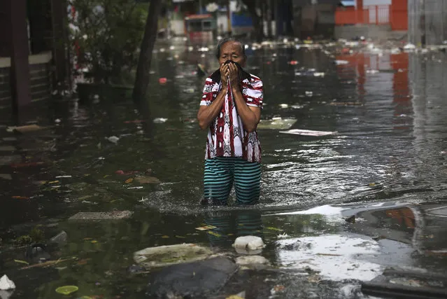 A woman reacts as she wades flood water in Jakarta, Indonesia, Saturday, January 4, 2020. Monsoon rains and rising rivers submerged parts of greater Jakarta and caused landslides in Bogor and Depok districts on the city's outskirts as well as in neighboring Lebak, which buried a number of people. (Photo by Dita Alangkara/AP Photo)