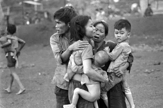 In this June 1965 photo, South Vietnamese civilians, among the few survivors of two days of heavy fighting, huddle together in the aftermath of an attack by government troops to retake the post at Dong Xoai, Vietnam