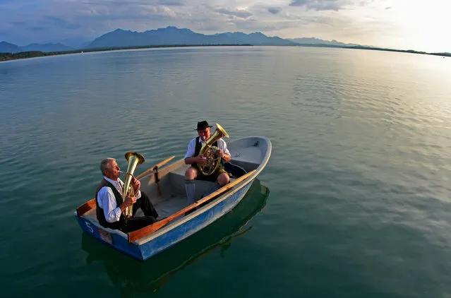 The musicians Josef Schuetzinger and Martin Schauer play their horns on the Chiemsee lake against the setting sun in Chieming, Germany, 22 July 2017. (Photo by Diether Endlicher/DPA/Bildfunk)