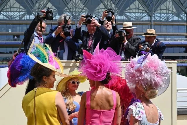 Race-goers wearing hats speak together as they are photographed during the thrid day, known as the Lady's day, of the Royal Ascot horse racing meet, in Ascot, west of London on June 16, 2022. (Photo by Justin Tallis/AFP Photo)