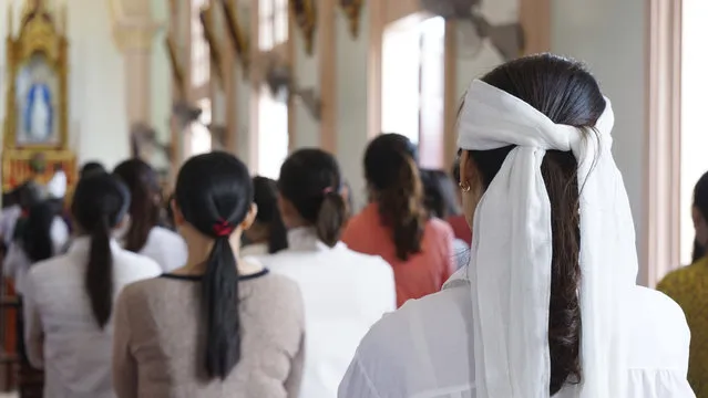 A woman wearing a white head band, traditionally worn by relatives of a deceased person during the funeral in Vietnam to show sign of mourning, attends a Sunday Mass at Phu Tang church in Yen Thanh district, Nghe An province, Vietnam Sunday, October 27, 2019. The attendees pray for the victims of the U.K truck deaths in which local villagers are feared to be among the ill-fated migrants. (Photo by Linh Do/AP Photo)