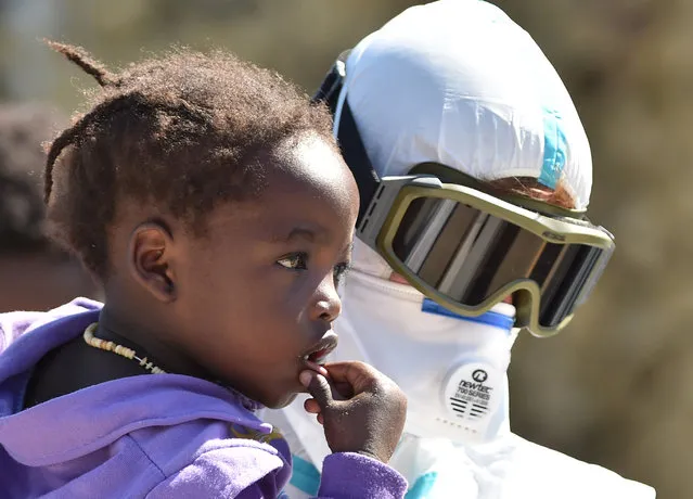 A crew member of the Irish Navy vessel LE Niamh holds a baby, who was rescued together other migrants, as they disembark at the Messina harbor in Sicily, Italy, Monday, August 24, 2015. (Photo by Carmelo Imbesi/AP Photo)