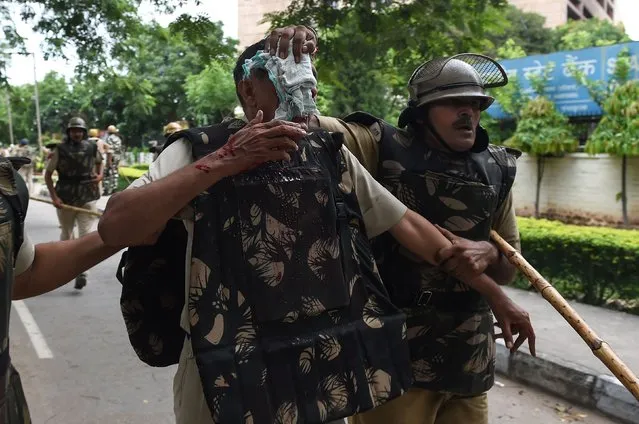 Indian security personnel help an injured colleague during clashes between the controversial guru's followers and security forces in Panchkula on August 25, 2017. (Photo by Money Sharma/AFP Photo)