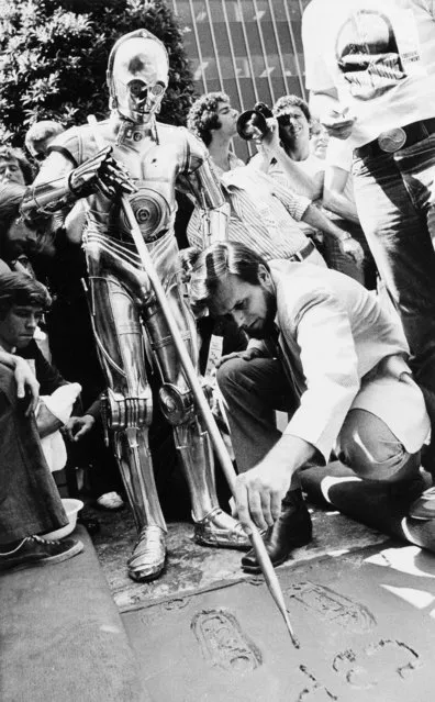 Joining movie stars of the past and present, C-3PO, one of the famous robots from the 20th Century-Fox film “Star Wars”, places his foot prints in the cement in front of Mann's Chinese Theater in Los Angeles, Calif., August 3, 1977. Assisted by studio personnel, C-3PO signs his name and thereby joins such stars as Greta Garbo, Clark Gable and Barbra Streisand. (Photo by Nick Ut/AP Photo)