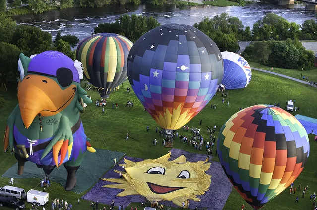 Balloons take to the skies from Simard Payne Memorial Park Friday, August 15, 2014, in Lewiston, Maine, during the launch of the 2014 Great Falls Balloon Festival. (Photo by Russ Dillingham/AP Photo/The Lewiston Sun-Journal)