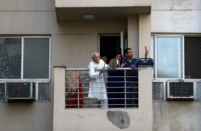 Residents clap and bang utensils from their balconies to cheer for emergency personnel and sanitation workers who are on the frontlines in the fight against coronavirus, in Noida, India, March 22, 2020. (Photo by Anushree Fadnavis/Reuters)