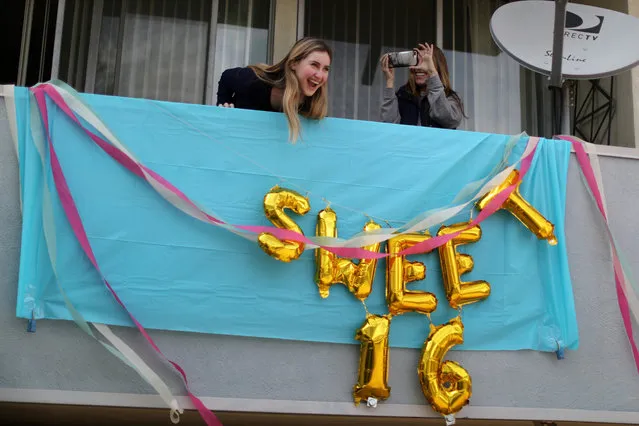 Lily Haines (L) celebrates her sixteenth birthday on her apartment balcony, watching her friends drive by with signs and balloons, as her mom, Suzanne Haines, takes photos, as the spread of the coronavirus disease (COVID-19) continues, in Los Angeles, California, U.S., April 8, 2020. (Photo by Lucy Nicholson/Reuters)