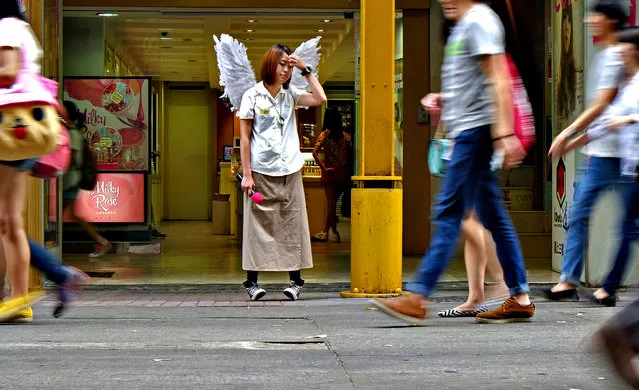 An employee wearing a pair of wings waits for her shift to end at Ximendin fashion district in Taipei, Taiwan, Thursday, August 28, 2014. (Photo by Wally Santana/AP Photo)