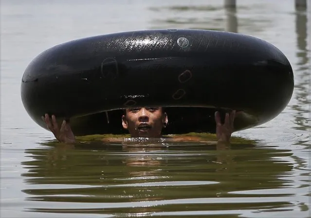 A boy uses an inner tube of a tyre to help him through flood water in Amarapura Township, near Mandalay, in Myanmar, 03 August 2016. The water level of the Ayeyarwaddy river in Mandalay passed the danger mark, flooding some villages in Amarapura township. Thousands of people from 16 villages have been affected and authorites closed the Yadanapon University in Amarapura township. According to media reports, flood victims are in serious need of medicine and food. (Photo by Hein Htet/EPA)